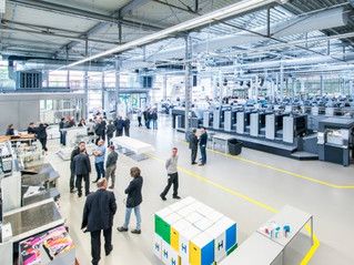 Halle mit mehreren Druckmaschinen von Heidelberg, Besucher und Mitarbeiter im Gespräch